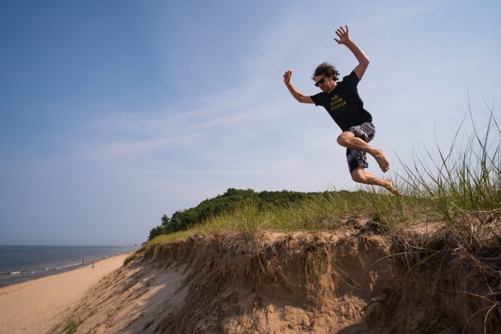 man in black t-shirt and black shorts jumping on brown rock during daytime